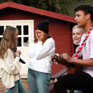 Eine Gruppe Jugendlicher lacht. Ein Junge spielt Gitarre.